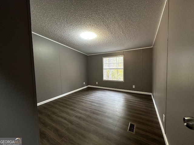 empty room with ornamental molding, dark hardwood / wood-style floors, and a textured ceiling