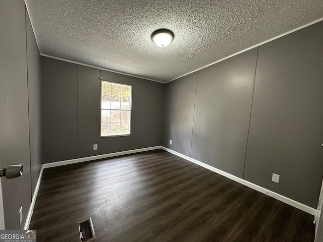 spare room featuring ornamental molding, dark wood-type flooring, and a textured ceiling