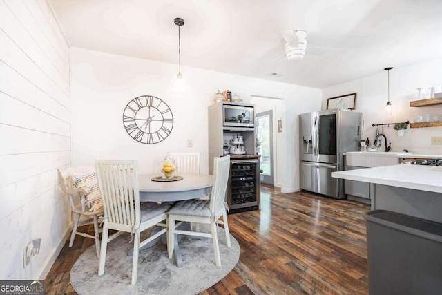 dining space featuring dark hardwood / wood-style flooring, ceiling fan, and beverage cooler