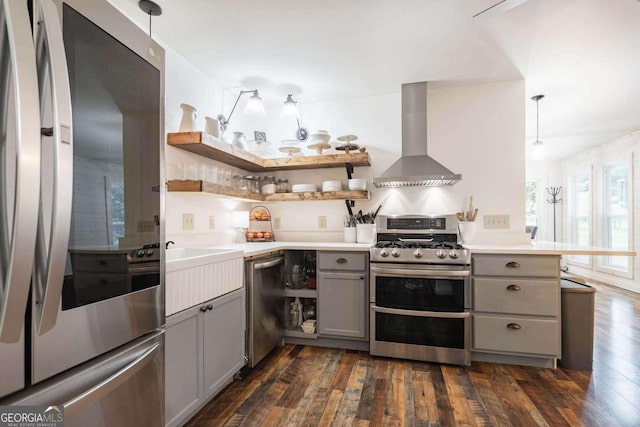 kitchen featuring stainless steel appliances, wall chimney exhaust hood, pendant lighting, and dark hardwood / wood-style floors