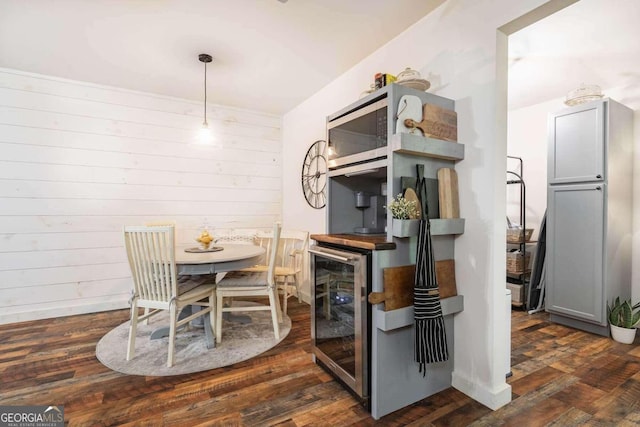 dining area featuring dark hardwood / wood-style flooring, wooden walls, and beverage cooler