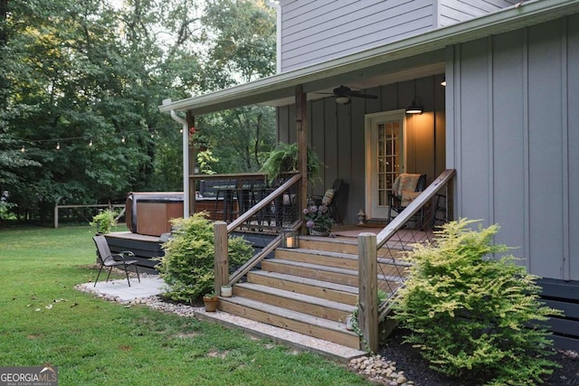 entrance to property with a hot tub, a lawn, and ceiling fan