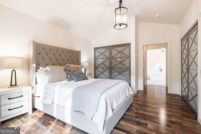 bedroom with lofted ceiling, dark hardwood / wood-style floors, and ensuite bath