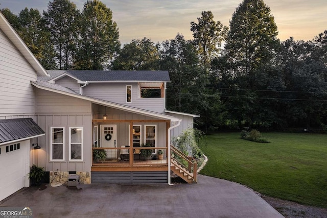 exterior space with a yard, a garage, and covered porch