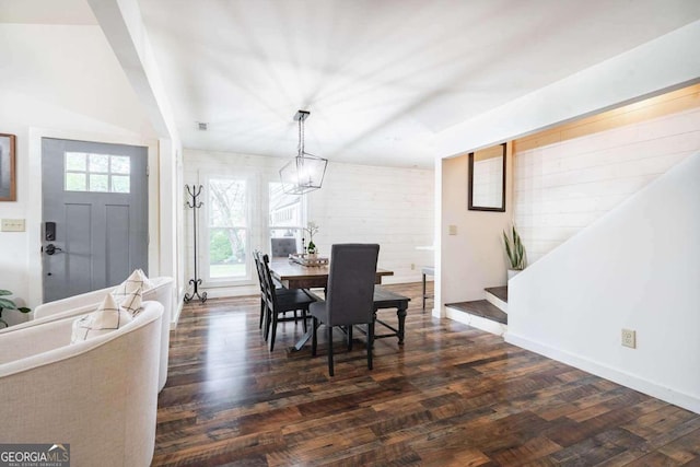 dining area featuring brick wall, dark wood-type flooring, and a chandelier