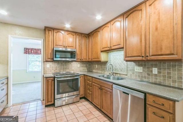 kitchen with appliances with stainless steel finishes, light tile patterned flooring, tasteful backsplash, and sink