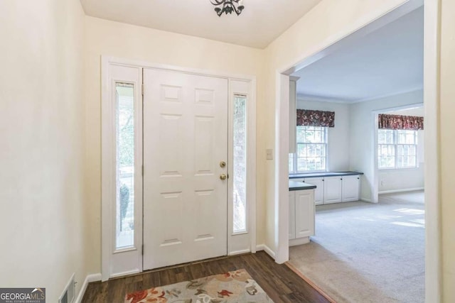 entryway with ornamental molding and dark wood-type flooring