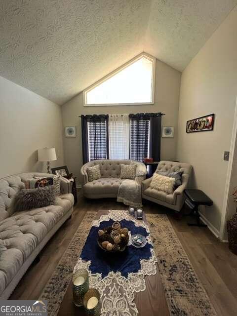 living room with lofted ceiling, hardwood / wood-style floors, and a textured ceiling