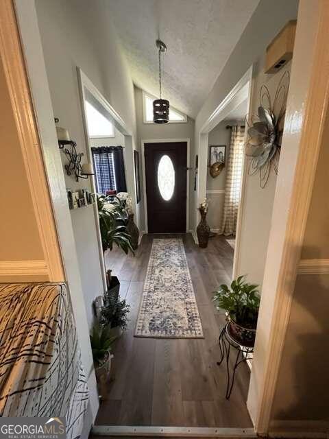 doorway with a textured ceiling, hardwood / wood-style flooring, and vaulted ceiling