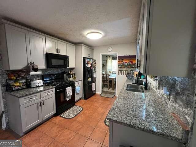 kitchen with a textured ceiling, black appliances, sink, and backsplash