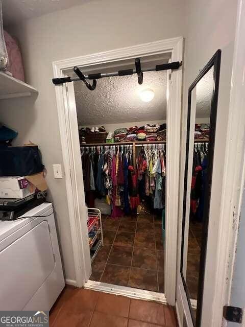 interior space with washer / dryer, a textured ceiling, and dark tile patterned floors