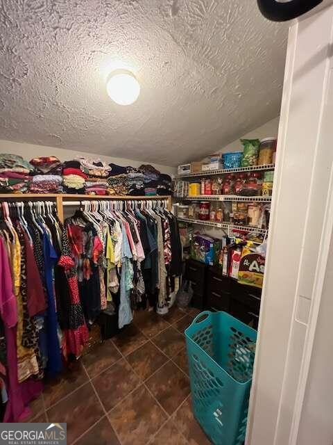 spacious closet with lofted ceiling and dark tile patterned floors