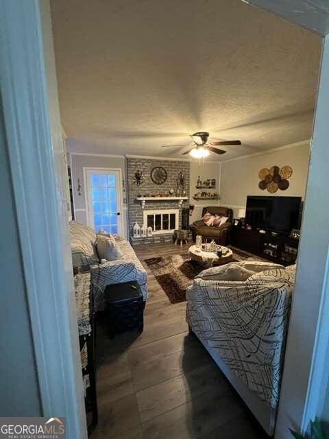 bedroom with ceiling fan, ornamental molding, a fireplace, and hardwood / wood-style floors