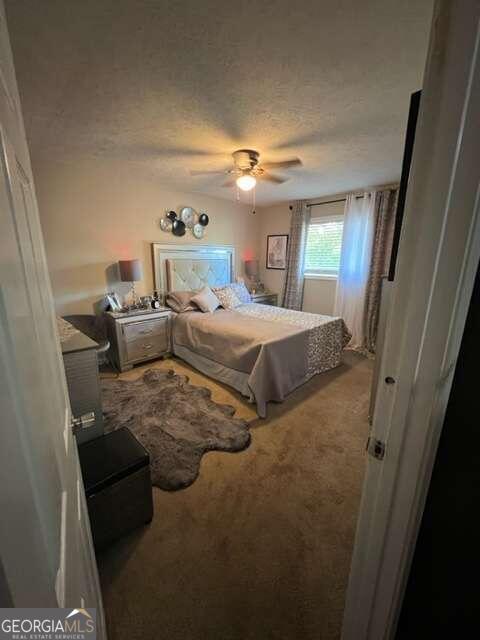 carpeted bedroom featuring a textured ceiling and ceiling fan