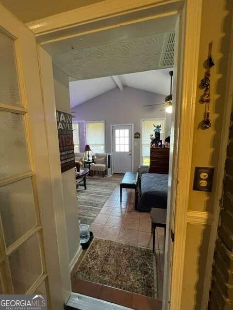 hall featuring tile patterned flooring and vaulted ceiling with beams