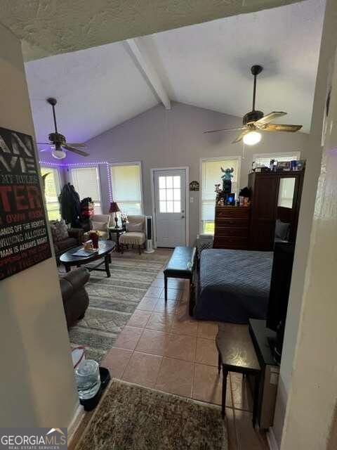 bedroom featuring vaulted ceiling with beams, light tile patterned floors, and ceiling fan