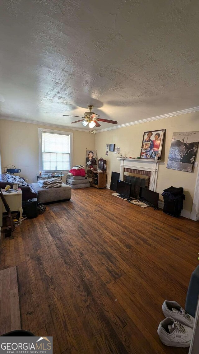 living room with a fireplace, hardwood / wood-style floors, crown molding, a textured ceiling, and ceiling fan