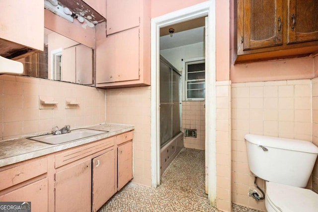 bathroom featuring tile patterned floors, toilet, tile walls, vanity, and walk in shower