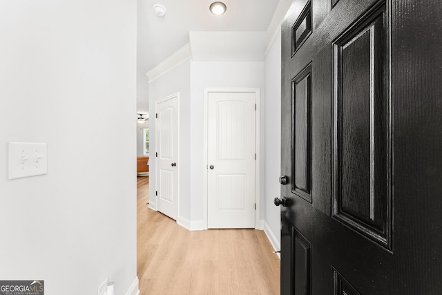 corridor with light hardwood / wood-style floors and ornamental molding