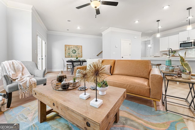 living room featuring crown molding, light wood-type flooring, and ceiling fan