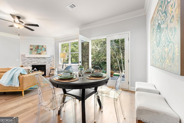 dining space with crown molding, light wood-type flooring, and a healthy amount of sunlight