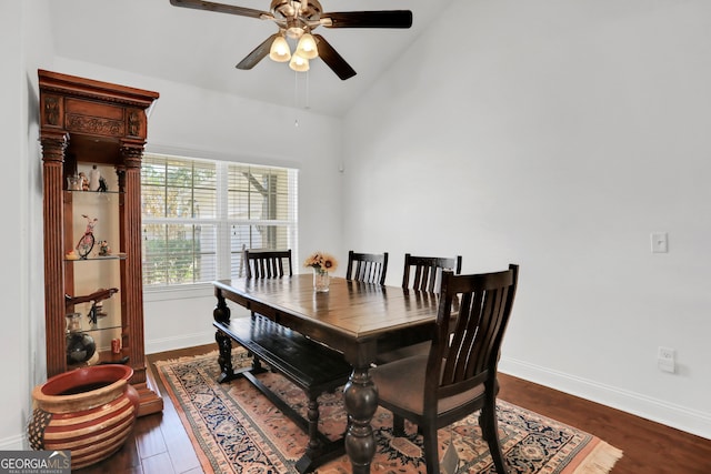 dining space with ceiling fan, vaulted ceiling, and dark hardwood / wood-style flooring