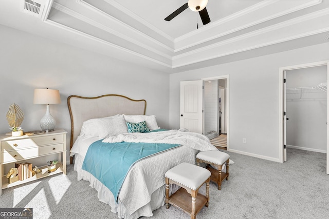 carpeted bedroom with a closet, a tray ceiling, a walk in closet, a towering ceiling, and ceiling fan