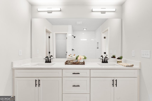 bathroom with a tile shower and vanity