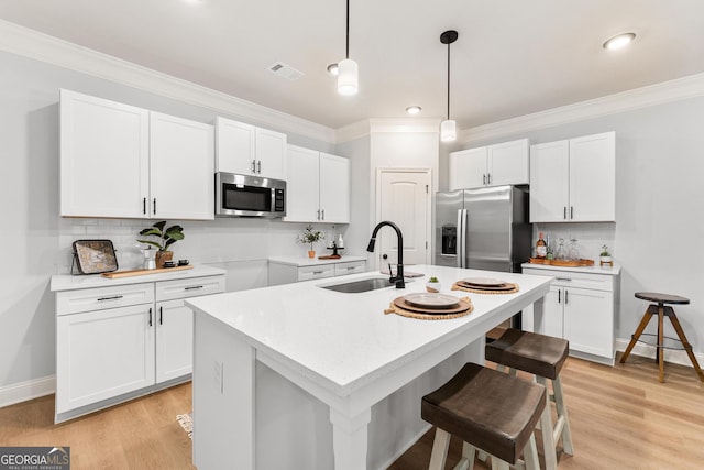 kitchen with sink, an island with sink, stainless steel appliances, and white cabinetry