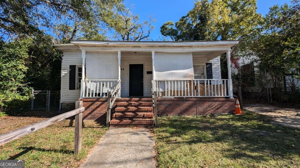 bungalow with covered porch and a front lawn