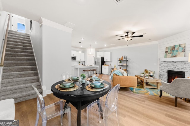 dining space featuring crown molding, light hardwood / wood-style flooring, and a fireplace