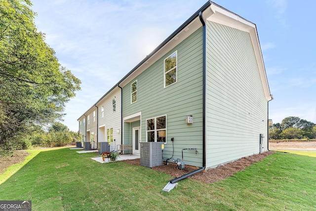 back of property with central AC, a patio, and a lawn