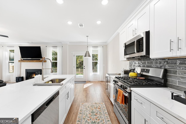 kitchen featuring appliances with stainless steel finishes, light hardwood / wood-style flooring, white cabinetry, and backsplash