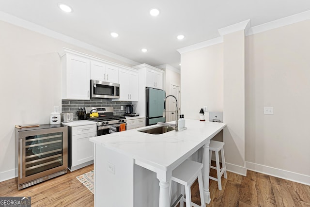 kitchen featuring appliances with stainless steel finishes, sink, backsplash, white cabinetry, and beverage cooler