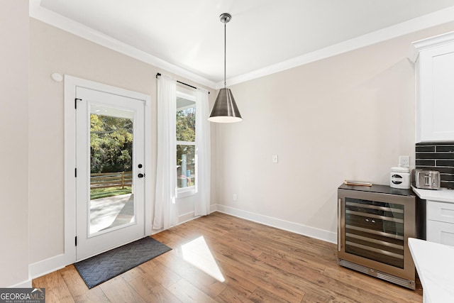 doorway featuring light hardwood / wood-style floors, crown molding, and beverage cooler