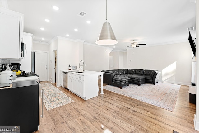 kitchen featuring white cabinets, stainless steel appliances, light wood-type flooring, and an island with sink