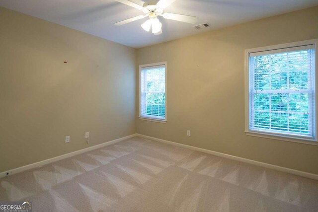 carpeted spare room with a healthy amount of sunlight and ceiling fan