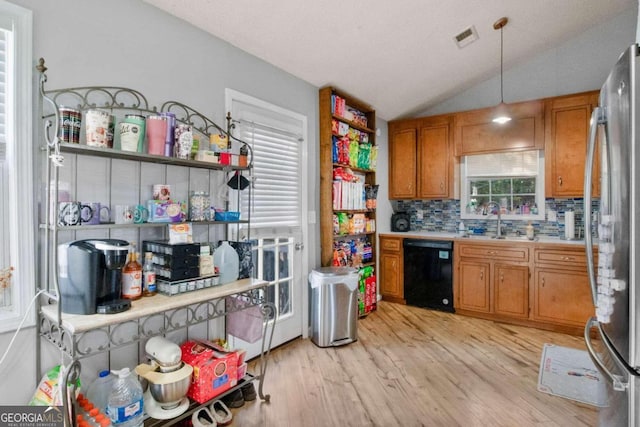 kitchen featuring black dishwasher, hanging light fixtures, vaulted ceiling, light hardwood / wood-style flooring, and sink