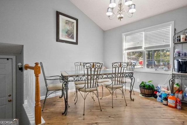 dining space with hardwood / wood-style flooring, vaulted ceiling, and an inviting chandelier