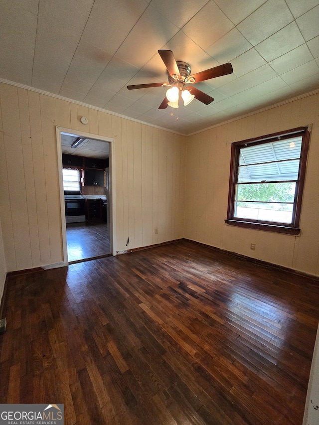 unfurnished room with ceiling fan, dark hardwood / wood-style flooring, and wooden walls