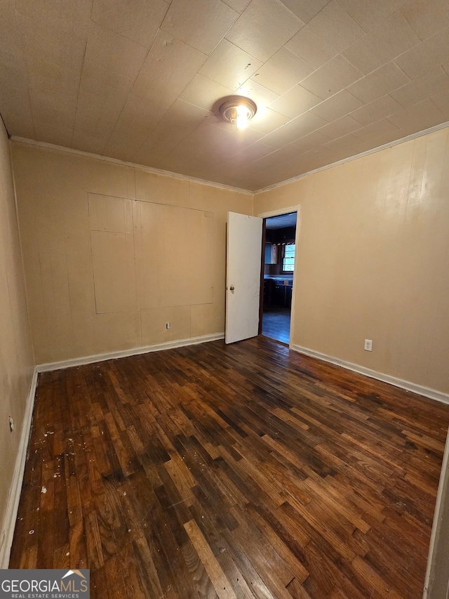 unfurnished room with dark wood-type flooring and crown molding