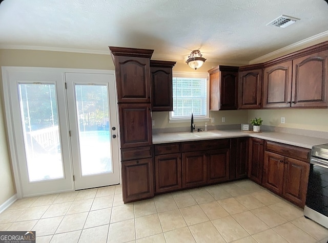 kitchen featuring stainless steel range, ornamental molding, sink, light tile patterned floors, and a textured ceiling