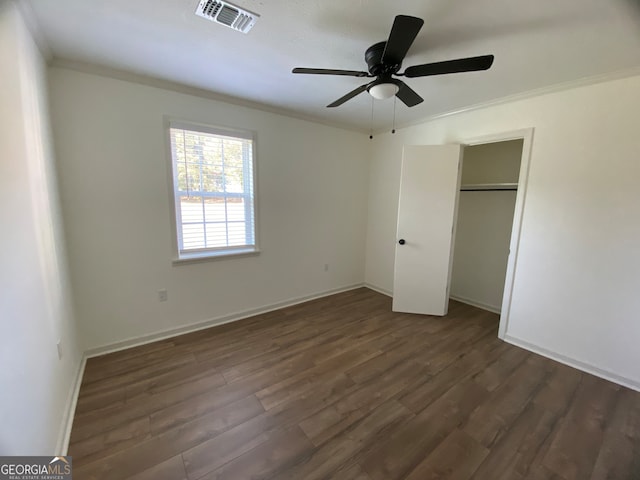 unfurnished bedroom featuring ornamental molding, a closet, dark hardwood / wood-style floors, and ceiling fan