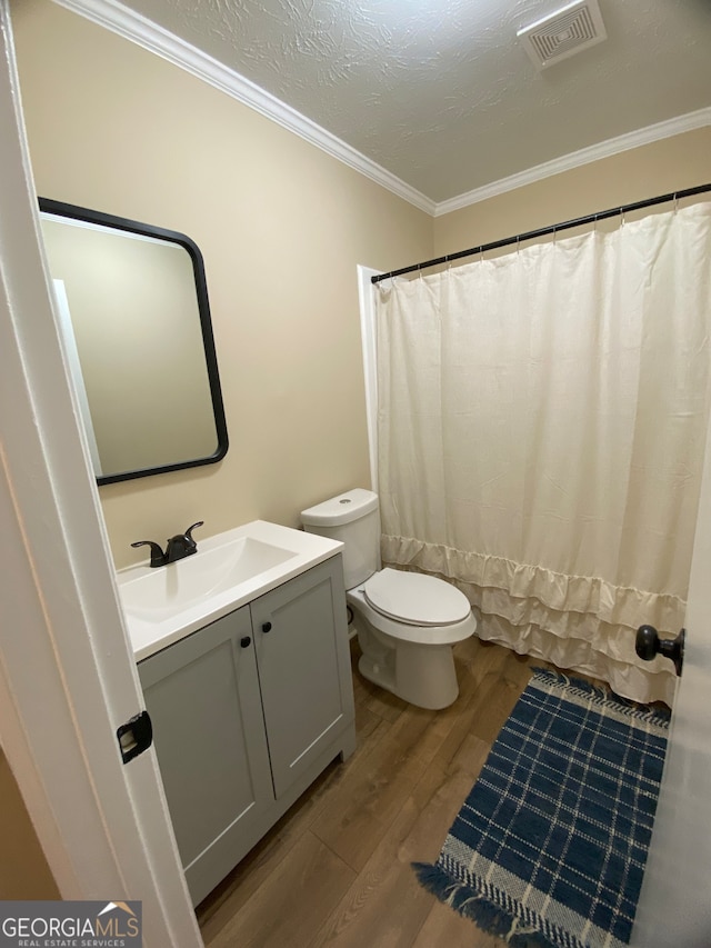 bathroom featuring hardwood / wood-style flooring, toilet, crown molding, vanity, and a textured ceiling