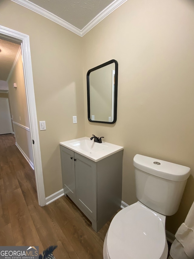 bathroom with vanity, crown molding, wood-type flooring, and toilet