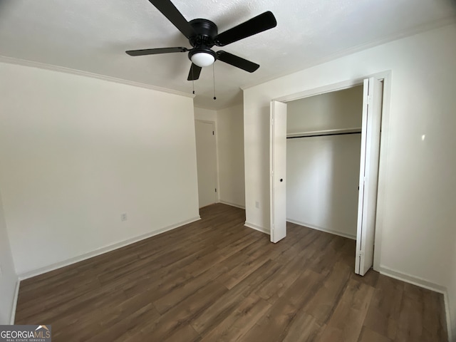 unfurnished bedroom featuring a closet, ornamental molding, dark wood-type flooring, and ceiling fan