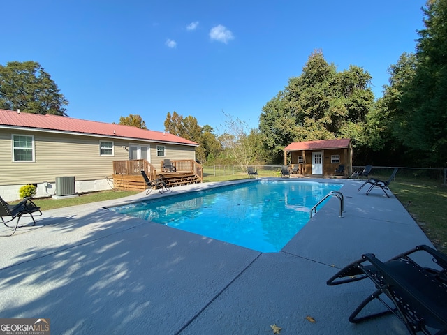 view of pool with cooling unit, a storage shed, a deck, and a patio