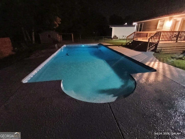 pool at twilight with a deck and a patio area