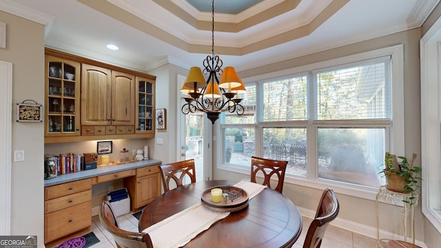 dining room with built in desk, light tile patterned floors, a raised ceiling, ornamental molding, and a chandelier