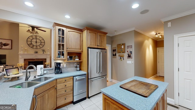 kitchen featuring light tile patterned floors, a sink, light countertops, appliances with stainless steel finishes, and glass insert cabinets